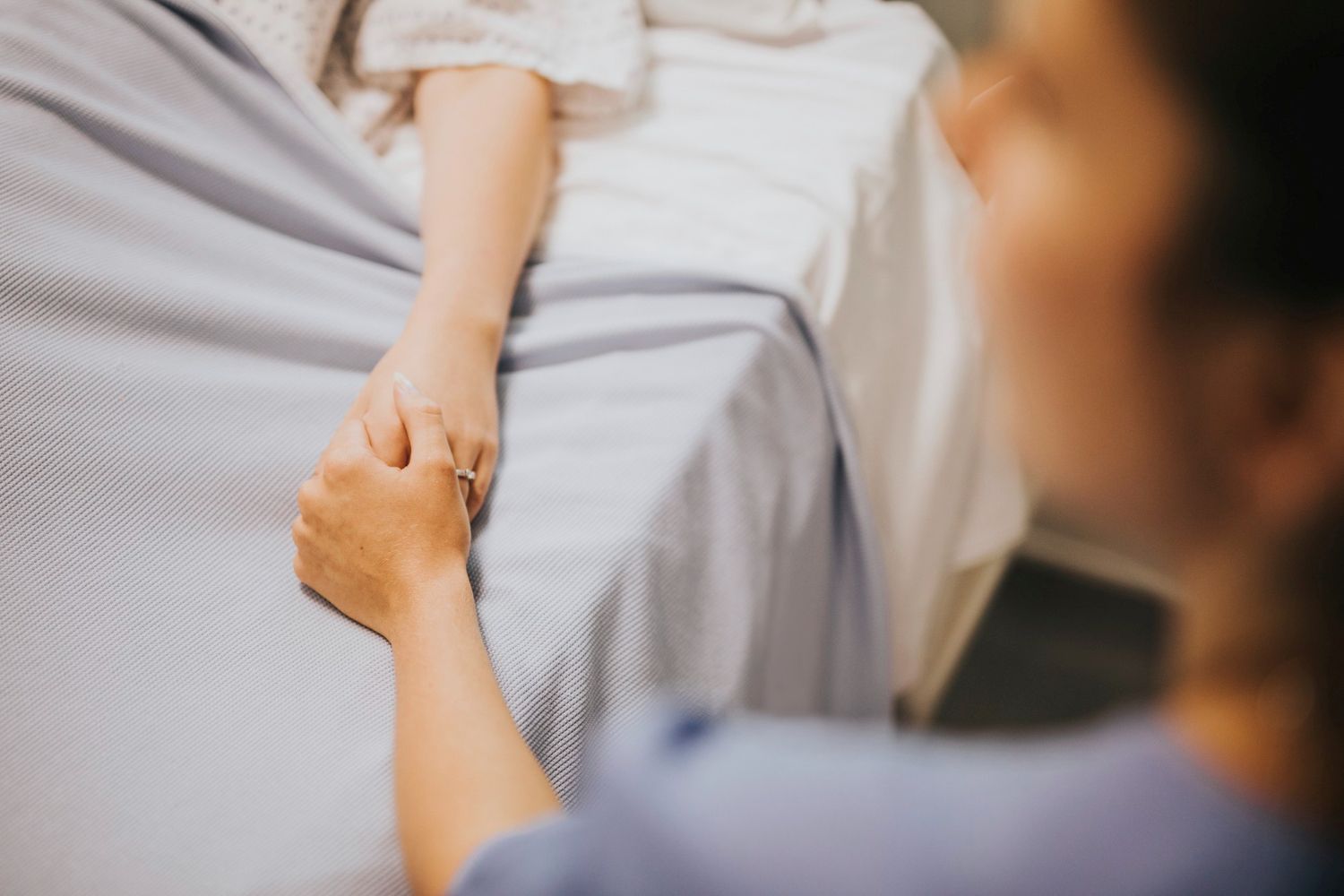 Someone holding womans hand in hospital